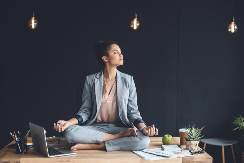 Business woman in suit meditating in dark office