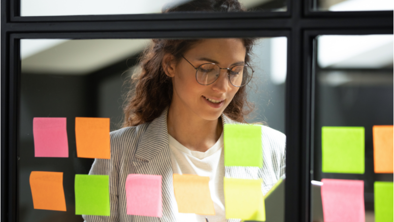 Woman writing sticky notes on office planning board