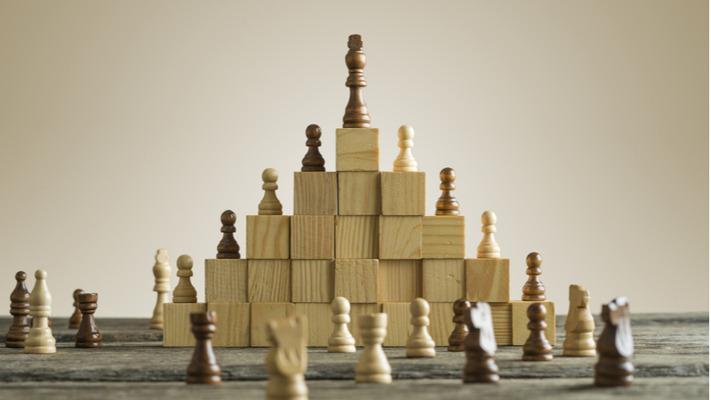 Chess pieces on wooden blocks with a leader on top