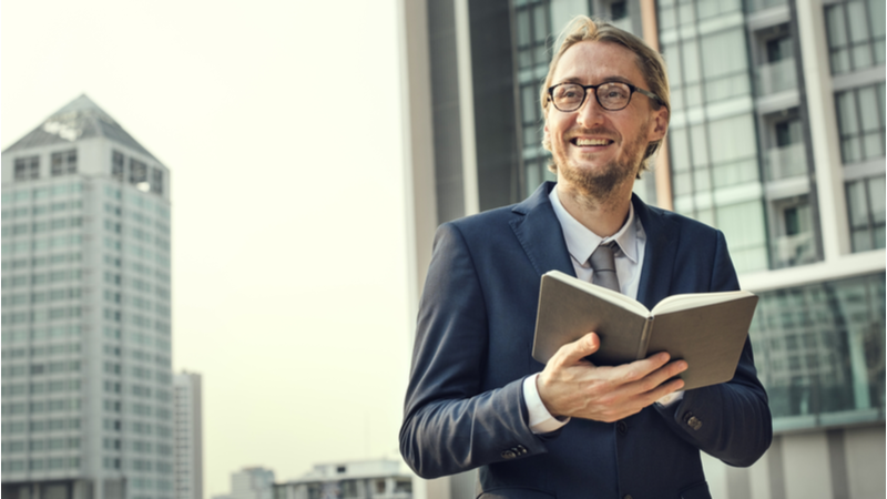business man in suit and glasses reading a book