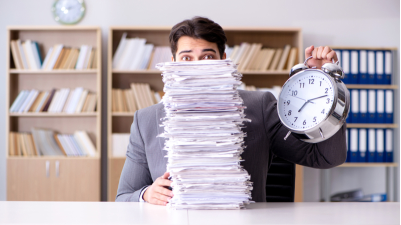 Man holding a pile of unfinished documents and rushing for deadline